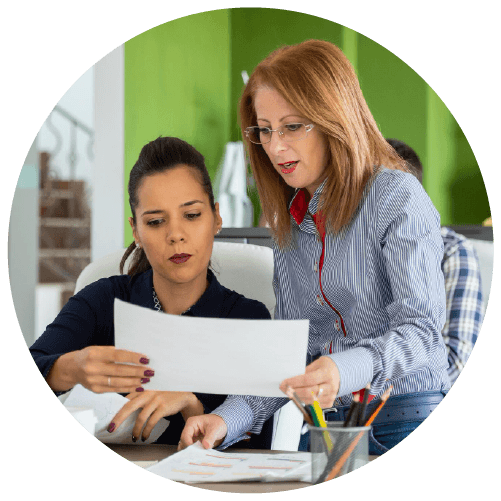 Two Womans Discussing While Holding a Piece of Paper